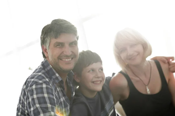 Ouders en hun zoon zitten opeengepakte in de woonkamer en lachende — Stockfoto