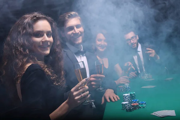 Grupo de amigos sentados à mesa de jogo no casino — Fotografia de Stock