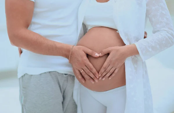 배에 심장 모양의 접힌 손을 가진 남편 과 임신 한 아내 — 스톡 사진