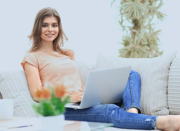 Kanepede oturan bir dizüstü bilgisayar ile güzel kız. — Stok fotoğraf