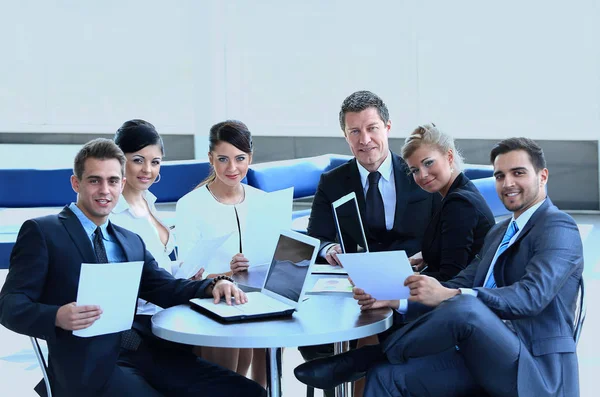 Grupp av affärsmän med dokument som sitter vid ett bord i lobbyn på banken. — Stockfoto