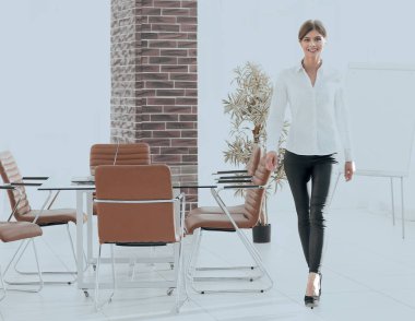 Gülümseyen genç bayan asistan ofiste dolaşıyor..