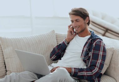 cep telefonu üzerinde konuşurken laptop ile ciddi genç adam