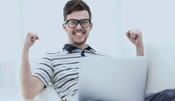 happy man with laptop sitting on the couch