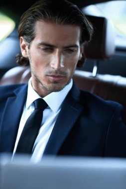 bir arabanın arka koltuğunda oturan adam onun laptop kullanma