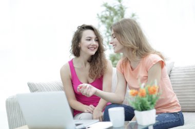 İki genç kadın kahve masasında konuşuyor ve oturuyor.