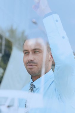 Camların arkasından manzara. Kendine güvenen iş adamı ofisinin penceresinden dışarı bakıyor.