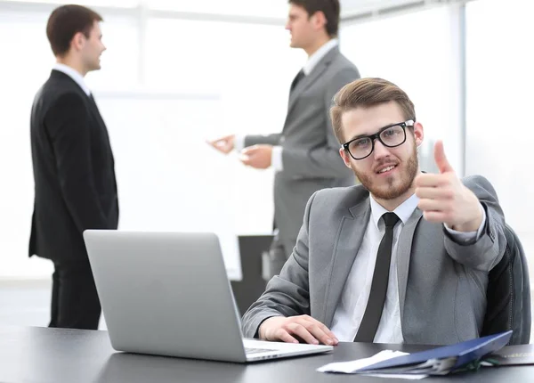 Gerente sentado en su escritorio y mostrando los pulgares hacia arriba — Foto de Stock