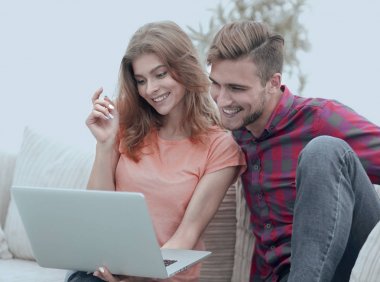oturma odasında dizüstü bilgisayarda bir Tv programı izlerken onun kız arkadaşı ile genç adam