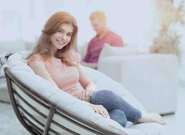 Mooie jonge vrouw zitten in een grote comfortabele stoel — Stockfoto