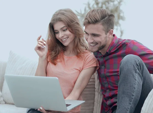 Ung man med hans flickvän tittar på en Tv-show på den bärbara datorn sitter i vardagsrummet — Stockfoto