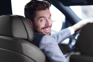 Dikiz aynası, genç adam arabasını sürüyor, kameraya bakıyor.