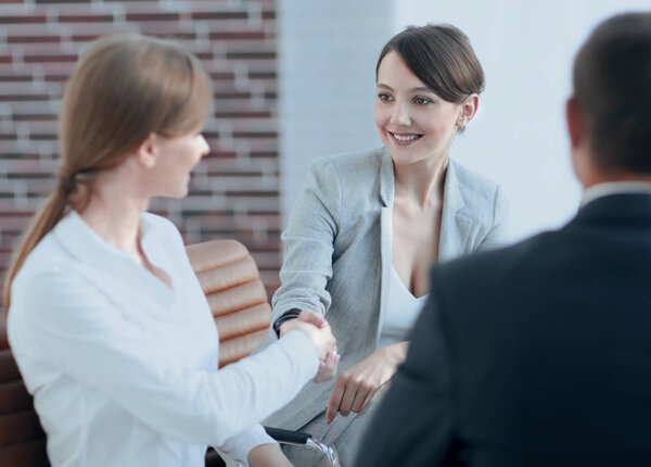 рукопожатие управляющего и клиента, сидящего за столом
