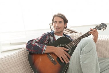 oturma odasında kanepede oturup gitar ile Modern adam.
