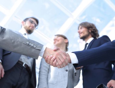 İş ortaklarının el sıkışması ön planda.