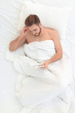 yatakta yatarken dijital tablet kullanan adam gülümseyen