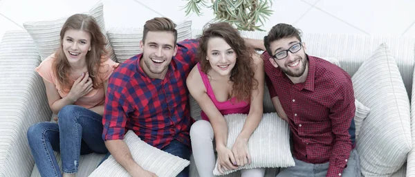 Alegre grupo de amigos ríen, sentado en el sofá . —  Fotos de Stock