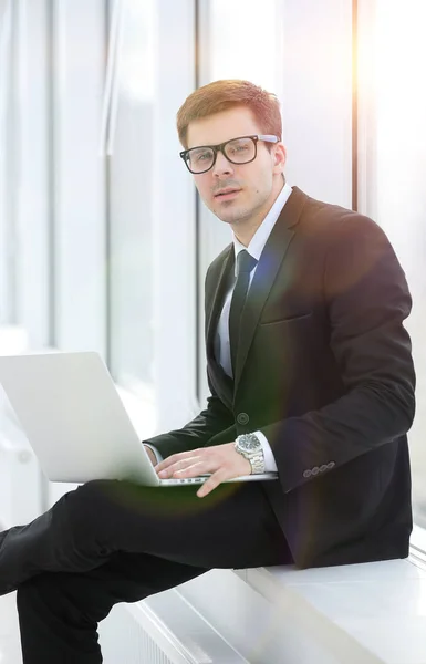 Νεαρού επαγγελματία με το laptop στο φόντο του παραθύρου του office — Φωτογραφία Αρχείου