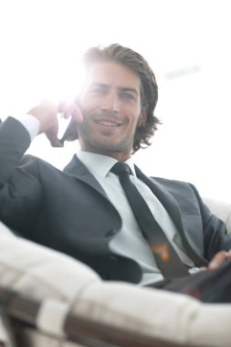 iş adamı rahat bir sandalyede otururken Smartphone'da konuşuyor.