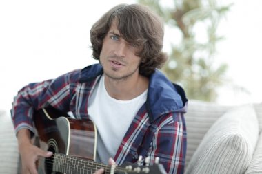 modern adam kanepede oturan gitar çalmak. bir yaşam tarzı kavramı