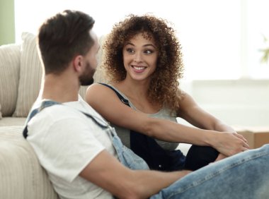 Yeni evliler yeni bir dairede kanepede oturuyor..