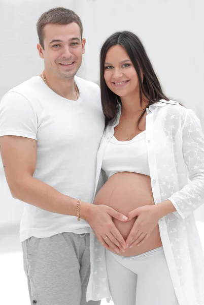 Man en zwangere vrouw met gevouwen handen in de vorm van een hart op zijn buik — Stockfoto