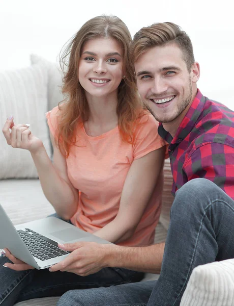 Pair students with a laptop sitting on sofa — Stock Photo, Image