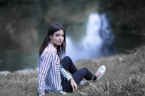 年轻女子坐在河边 — 图库照片