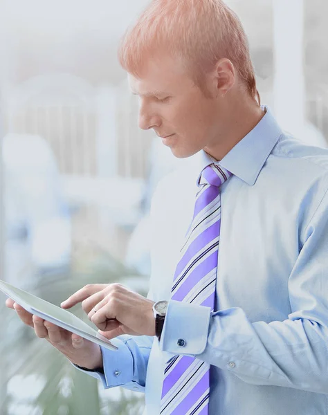 Knappe jonge man in een blauw shirt met behulp van een tablet — Stockfoto