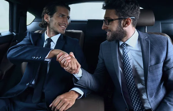 車の中で座っているビジネス パートナーの握手 — ストック写真
