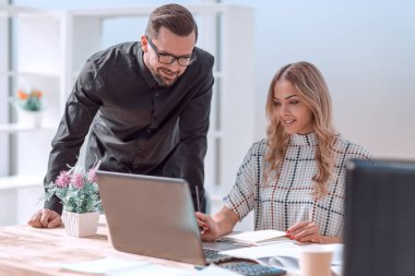 İş arkadaşları belgelerle çalışmak için dizüstü bilgisayar kullanıyor.