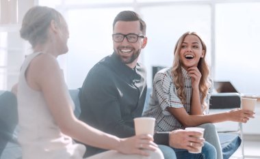 Kahve bardaklı şirket çalışanları lobide oturuyorlar.