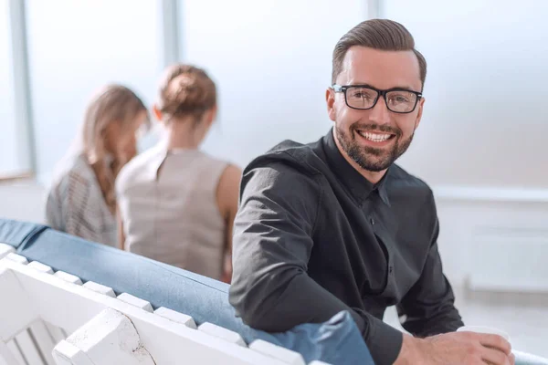 Jonge zakenman met een kopje koffie zittend in een modern kantoor. — Stockfoto