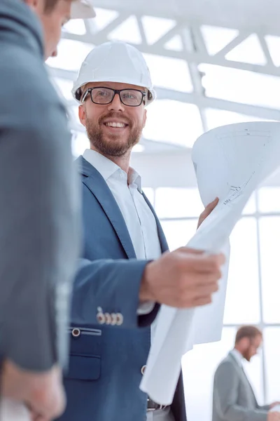 De cerca. arquitecto sonriente con plano de pie en la oficina — Foto de Stock