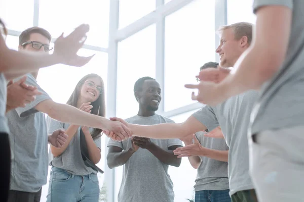 Jongeren schudden elkaar de hand, staan in een vriendenkring. — Stockfoto