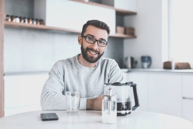 çekici bir adam sabahleyin mutfak masasında oturuyor.