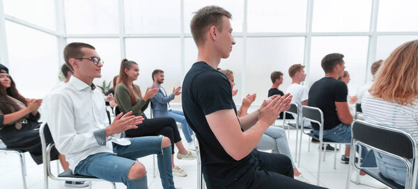 вид сзади. молодые люди аплодируют во время молодежного семинара.