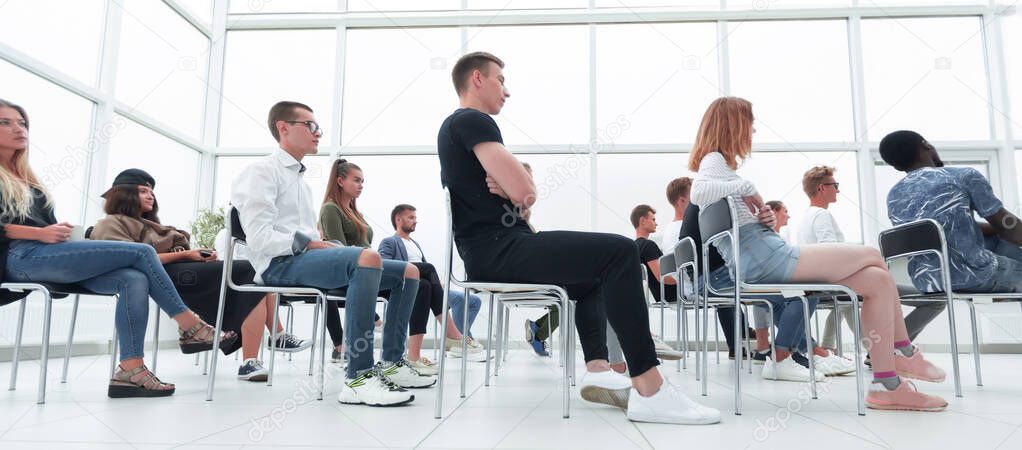 group of young people sitting in a bright conference room.