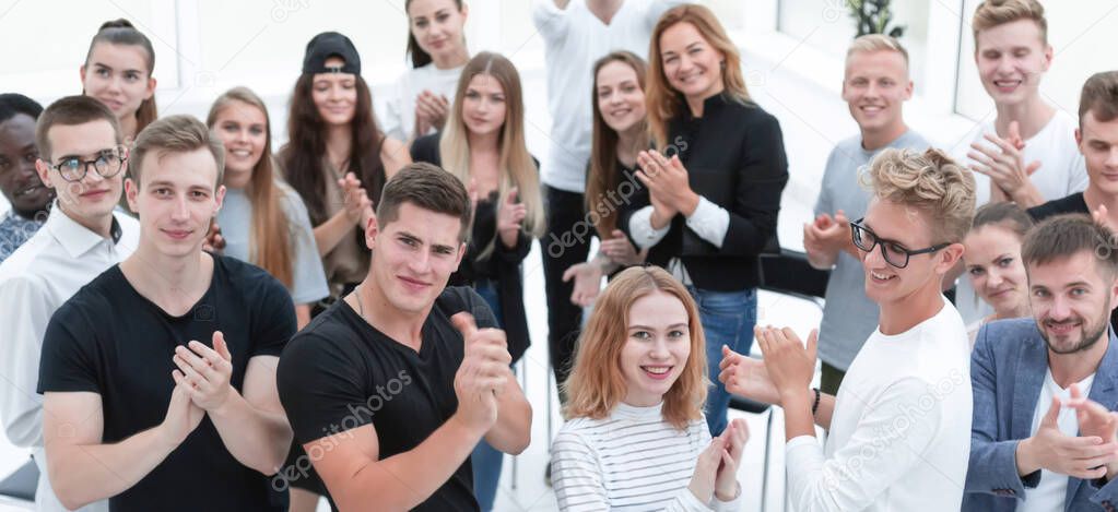 group of smiling young people applaud together