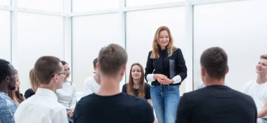 Genç bir kadın bir grup gençle iş eğitimi yapıyor..