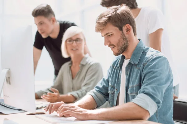 Group of designers with sketches standing near the desktop — Stock Photo, Image