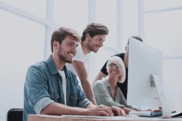 Smiling young man standing near the office Desk — Stock Photo, Image