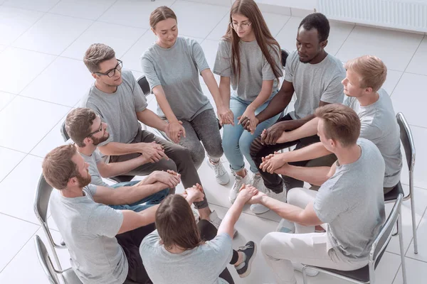 Jóvenes tomándose de las manos en una reunión de grupo. — Foto de Stock