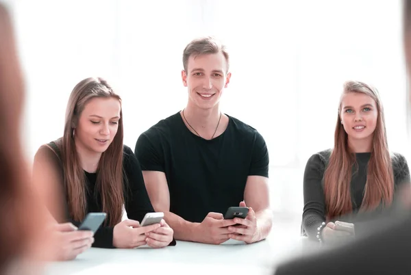 Gruppe junger Leute sitzt an einem runden Tisch — Stockfoto