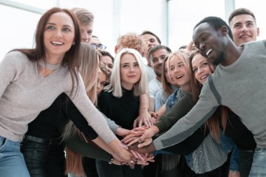 Çeşitli gençler ellerini birleştiriyor.