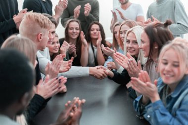 Masada oturan bir grup genç alkışlıyor. .
