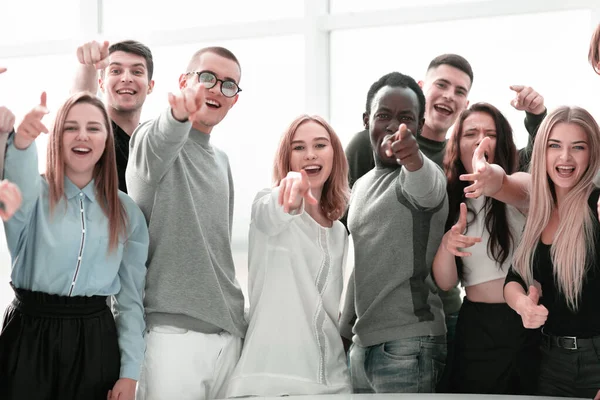 Группа улыбающихся молодых людей, указывающих на какой-то момент — стоковое фото