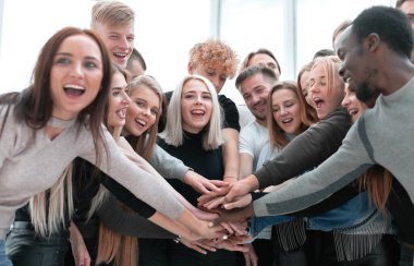 Çeşitli gençler ellerini birleştiriyor.