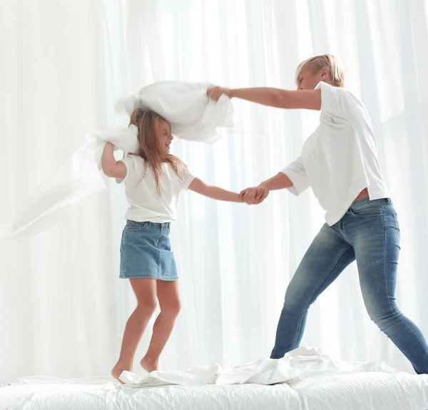 close up. mom and daughter have a pillow fight on the bed