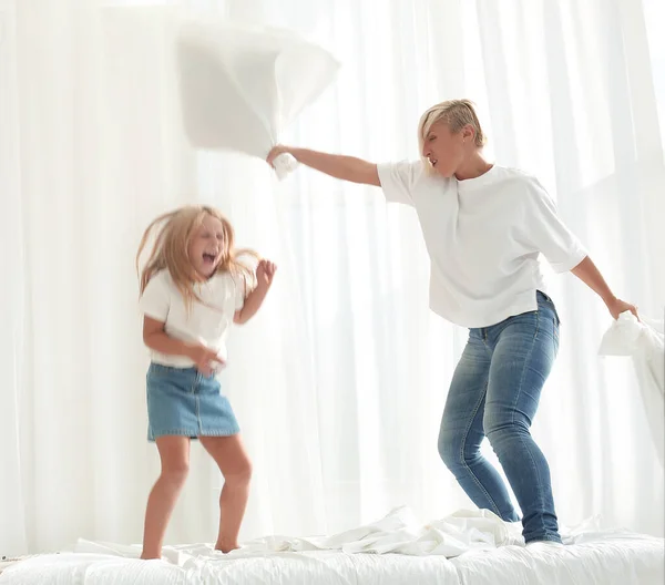 close up. mom and daughter have a pillow fight on the bed